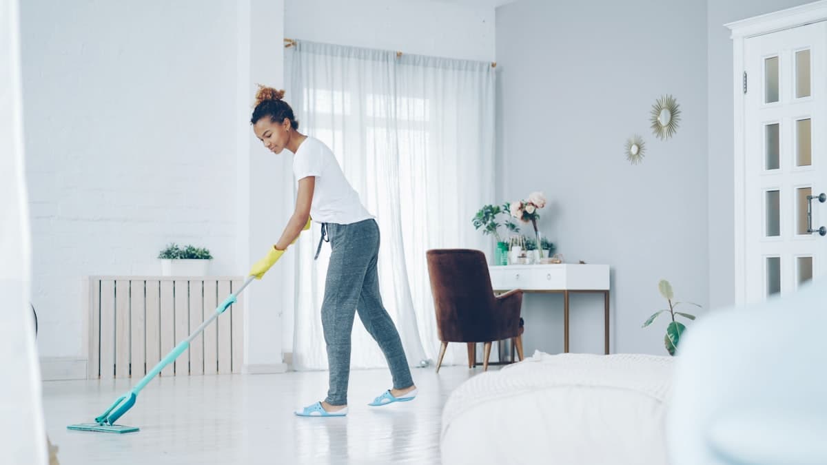 Professional cleaner mopping the floor of a bright, modern Bangkok condo