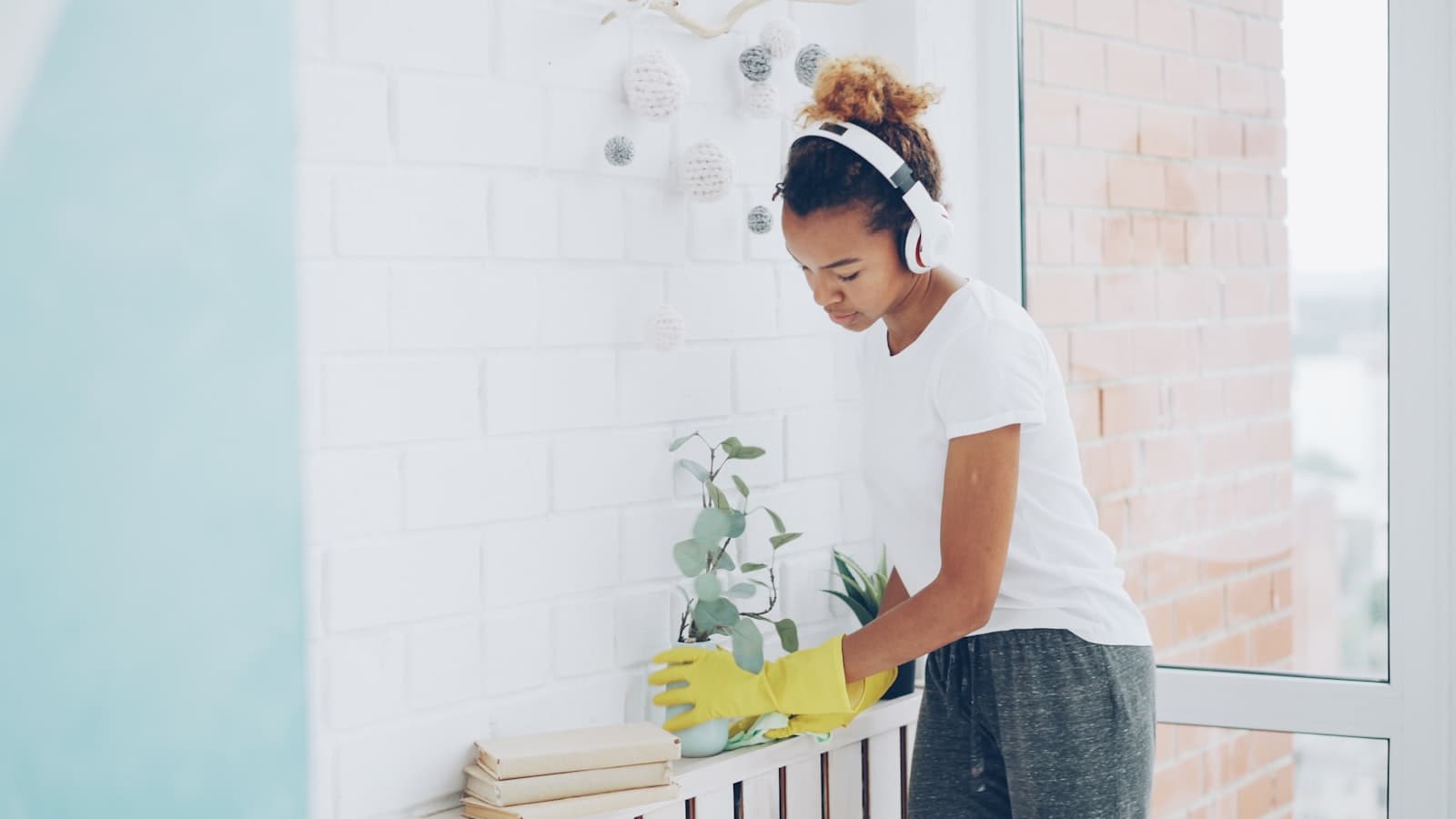 Cleaner dusting shelves beside a high-rise condo window